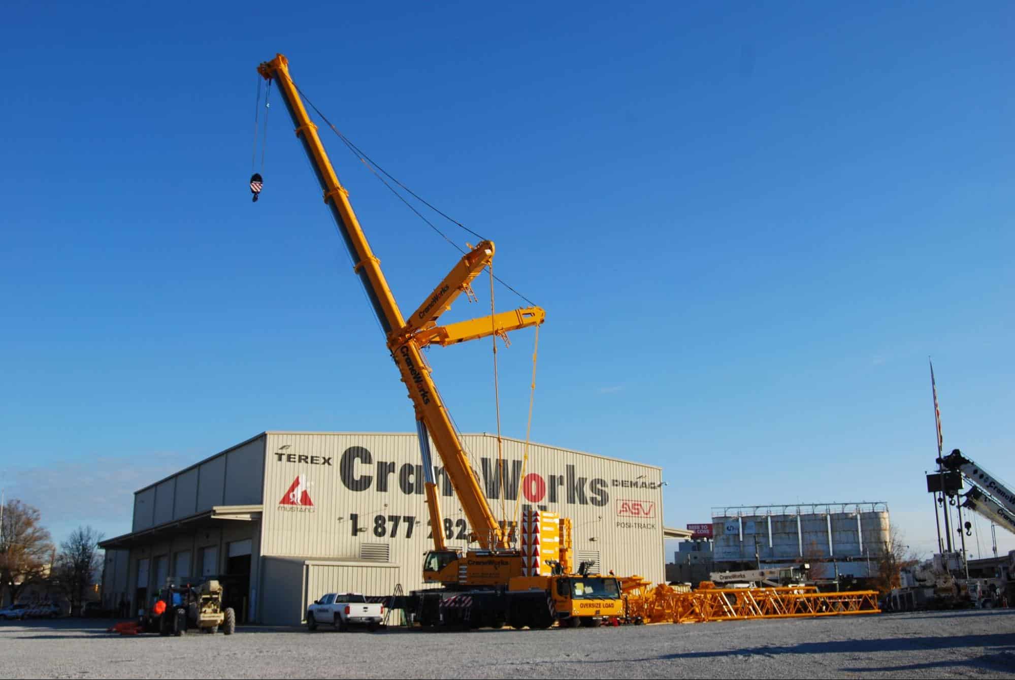 A Yellow Crane Sitting In Front Of A CraneWorks Warehouse.